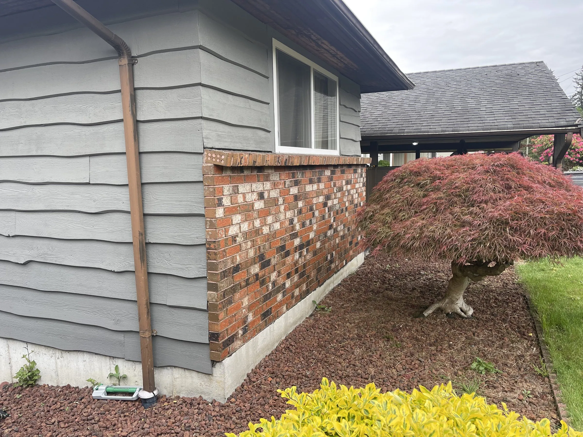 Before: Grey house front with new siding below the window