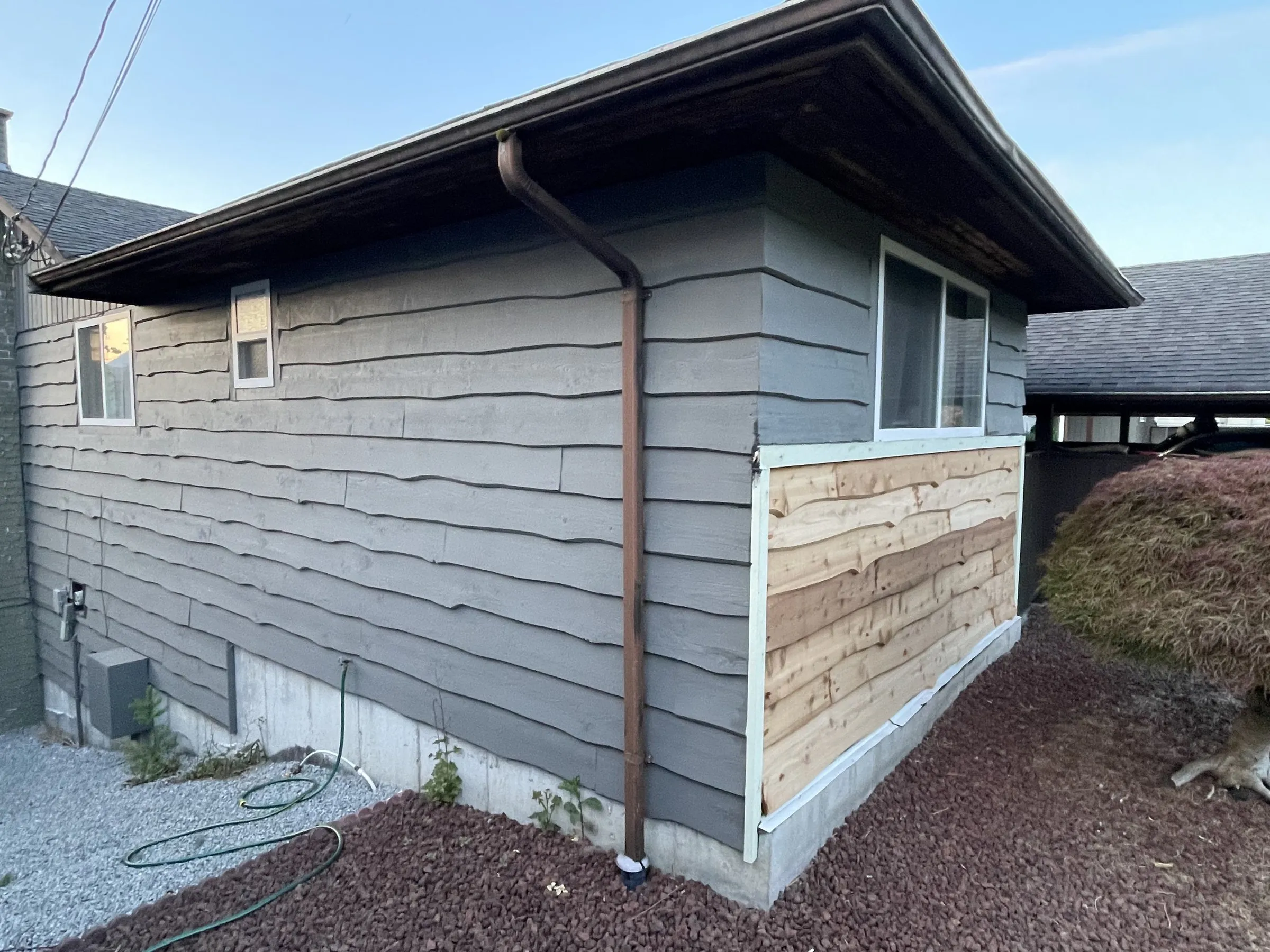 After: Grey house front with new siding below the window