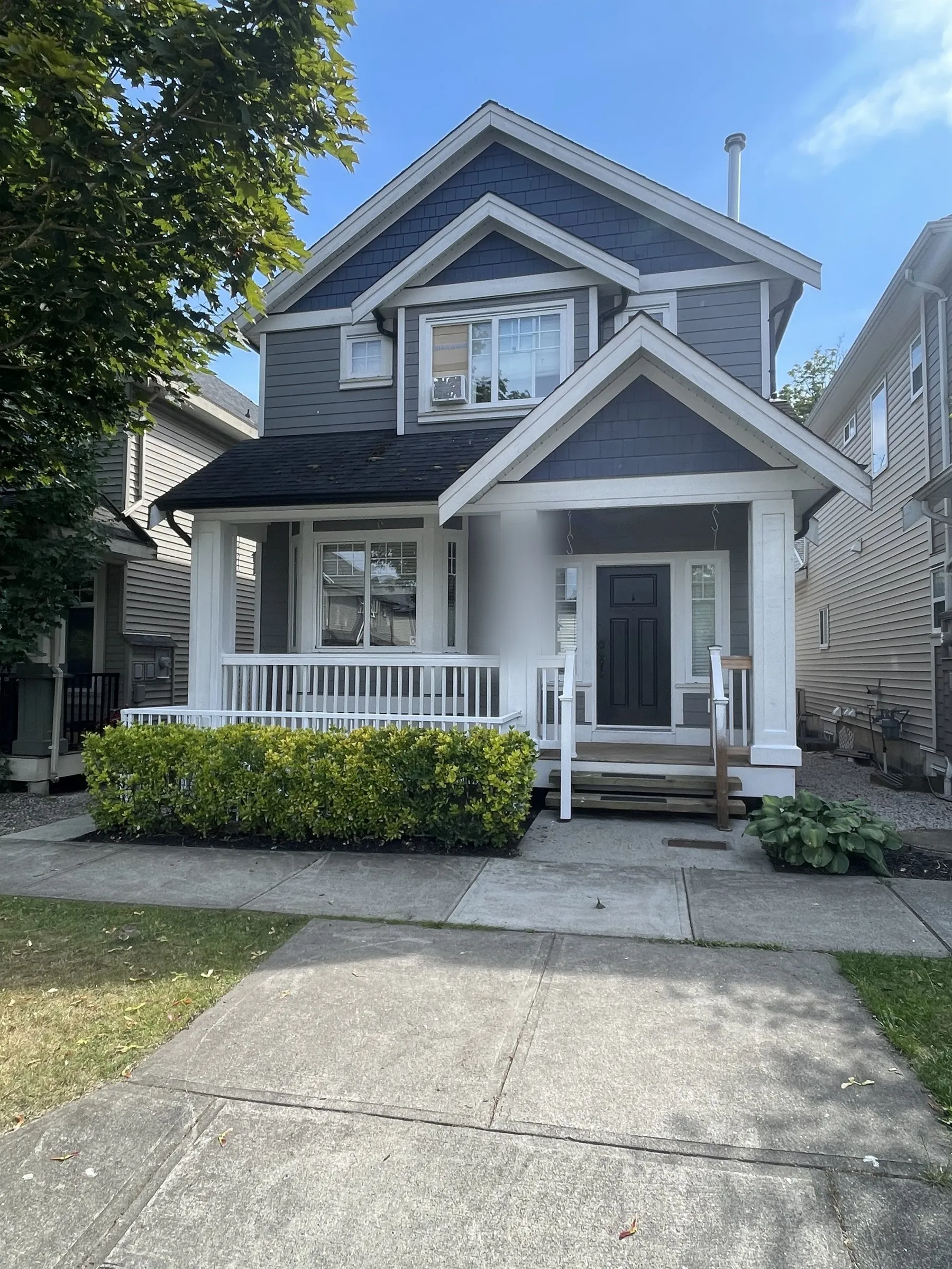 Before: Two-storey blue house with freshly painted white porch and trim